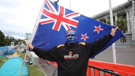 A protester holds a New Zealand flag standing in front of Parliament buildings on the fourth day of demonstrations against Covid-19 restrictions in Wellington on February 11.