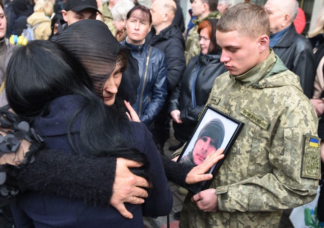 Relatives embrace the funeral of Ukrainian soldier Theodore Osadchy at the Lychakiv cemetery in Lviv, western Ukraine, on March 29, 2022.