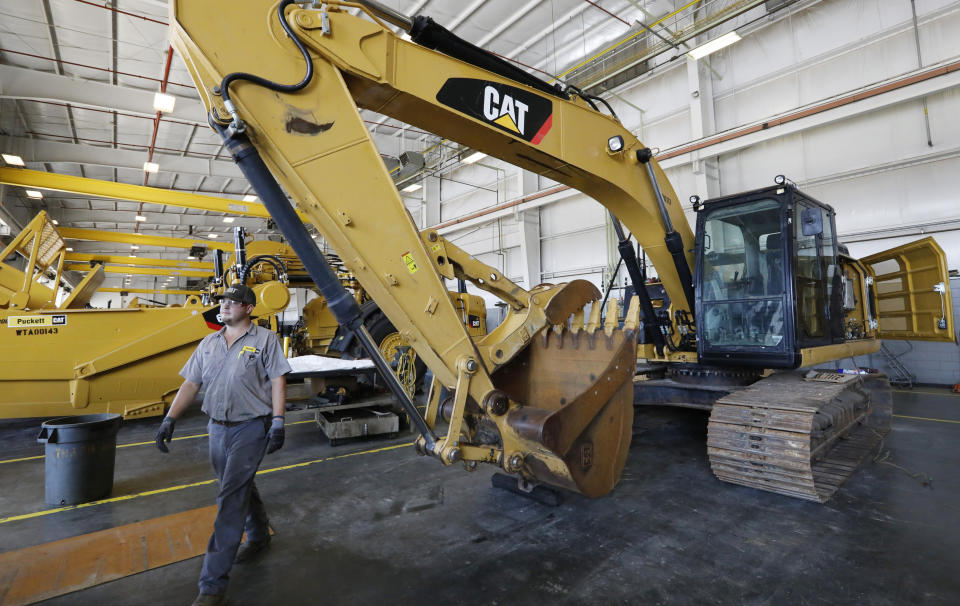 FILE - A Puckett Machinery technician passes in front of a new heavy-duty Caterpillar excavator awaiting modification at the Puckett Machinery Company in Flowood, Miss..  September 18, 2019. Caterpillar continued to see a healthy boom in sales during the fourth quarter of 2022, as the economy strengthens.  Sales increased 23% to $13.8 billion.  (AP Photo/Rogelio V. Solis)