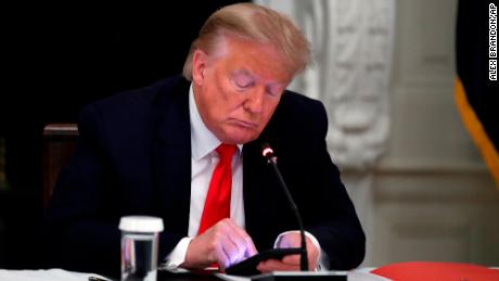 Former President Donald Trump looks at his phone during a roundtable with state governors about reopening small businesses in America, in the dining room of the White House in Washington, June 18, 2020. 
