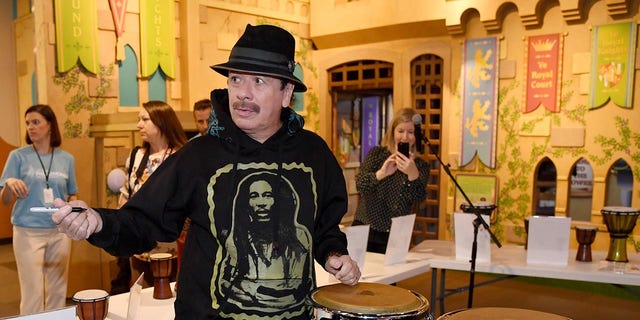Artist Carlos Santana signs congressional autographs donated by him and his wife Cindy Blackman Santana to the Las Vegas Philharmonic as they participate in the Philharmonic Orchestra's global version of the orKIDStra music education program for a group of students at the Children's Museum of Discovery on October 29, 2019 in Las Vegas, Nevada.  (Photo by Ethan Miller/Getty Images)