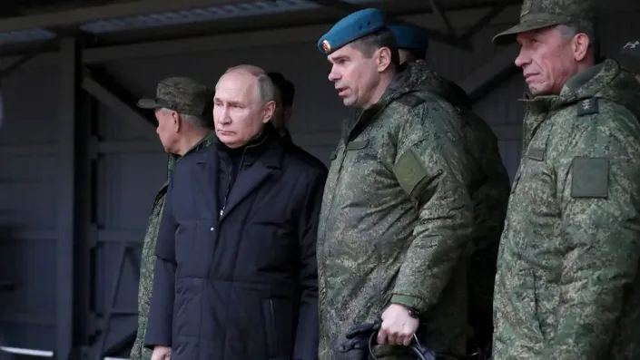 Putin stands next to the soldier under a roofed area